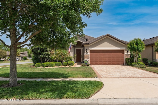 view of front of home with a garage, stucco siding, decorative driveway, and a front yard