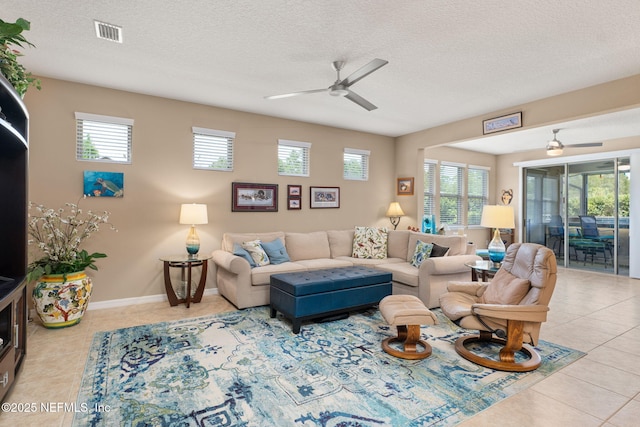 living room featuring tile patterned floors, visible vents, ceiling fan, and a wealth of natural light