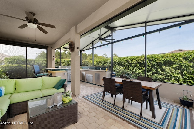 sunroom with outdoor dining area, a ceiling fan, outdoor lounge area, and an outdoor kitchen