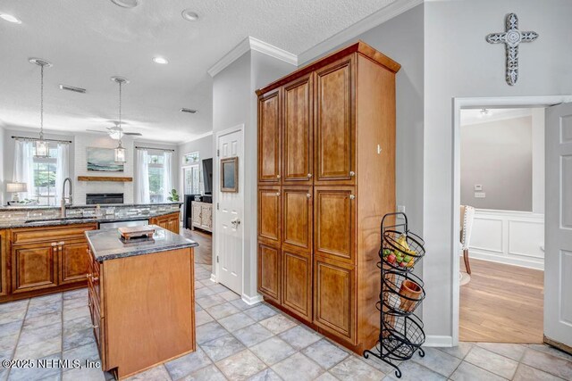 1104 Creekwood Way, Saint Johns, FL 32259 - kitchen with brown cabinetry, ornamental molding, ceiling fan, a brick fireplace, and a center island