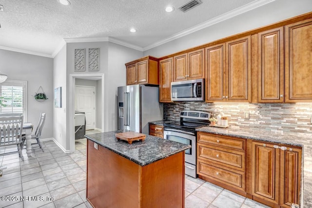 1104 Creekwood Way, Saint Johns, FL 32259 - kitchen with appliances with stainless steel finishes, brown cabinets, tasteful backsplash, a center island, and dark stone counters