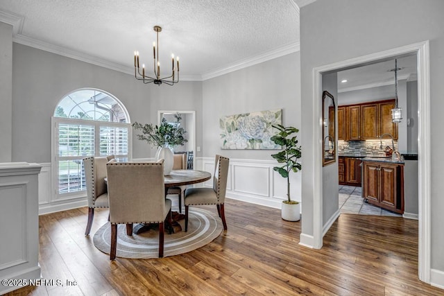 1104 Creekwood Way, Saint Johns, FL 32259 - dining area featuring a chandelier, wood-type flooring, crown molding, a textured ceiling, and a wainscoted wall