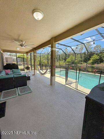 view of patio featuring a lanai, outdoor lounge area, an outdoor pool, and a ceiling fan