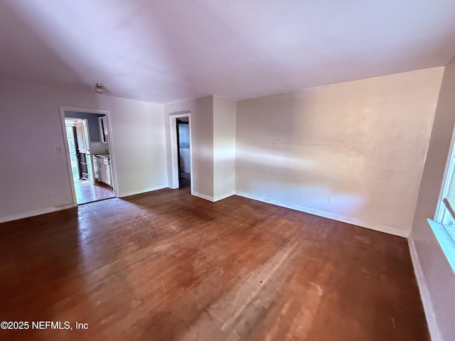 unfurnished room featuring baseboards and dark wood finished floors