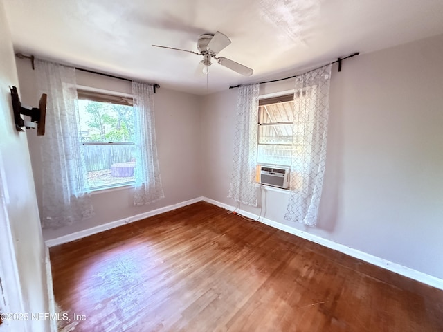 empty room featuring baseboards, cooling unit, a ceiling fan, and wood finished floors