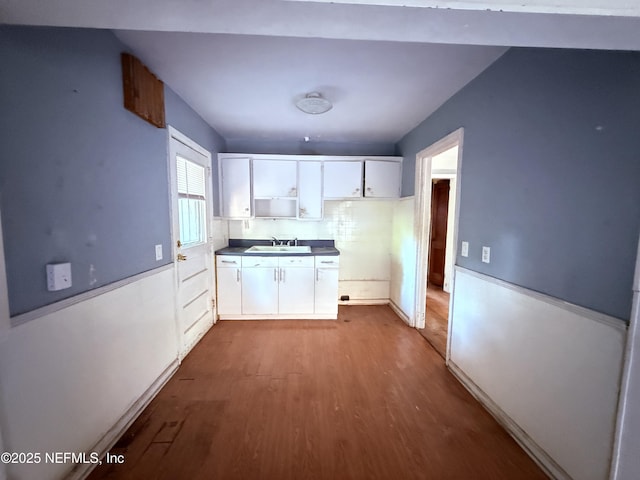 kitchen with white cabinets, dark countertops, dark wood finished floors, and a sink