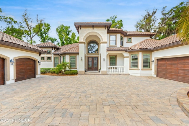 106 Villa Sovana Ct, Saint Johns, FL 32259 - mediterranean / spanish house featuring an attached garage, french doors, stucco siding, a tiled roof, and decorative driveway