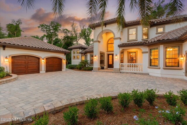 106 Villa Sovana Ct, Saint Johns, FL 32259 - mediterranean / spanish house featuring decorative driveway, covered porch, an attached garage, stucco siding, and a tile roof