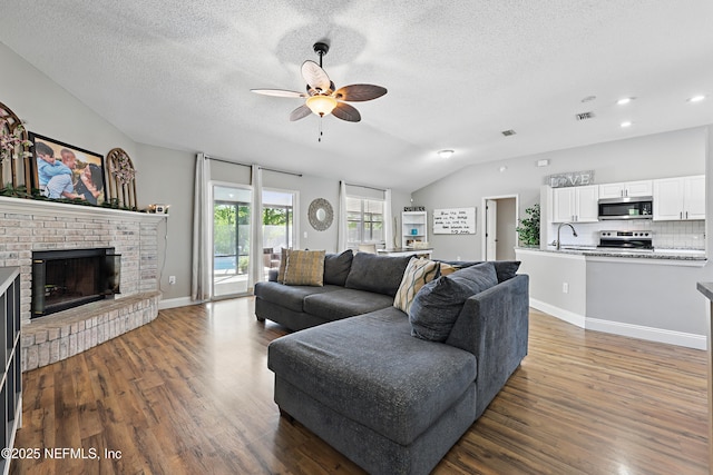 living room with vaulted ceiling, wood finished floors, a textured ceiling, and ceiling fan