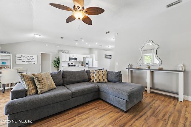 living area with lofted ceiling, a ceiling fan, wood finished floors, and visible vents