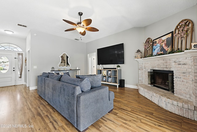 living room with wood finished floors, baseboards, a ceiling fan, and visible vents