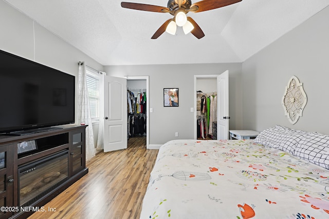 bedroom featuring a spacious closet, a ceiling fan, light wood-type flooring, a closet, and baseboards