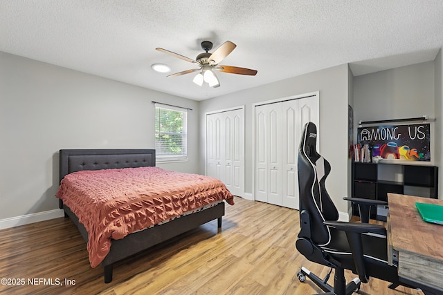 bedroom featuring ceiling fan, baseboards, light wood-style floors, and two closets