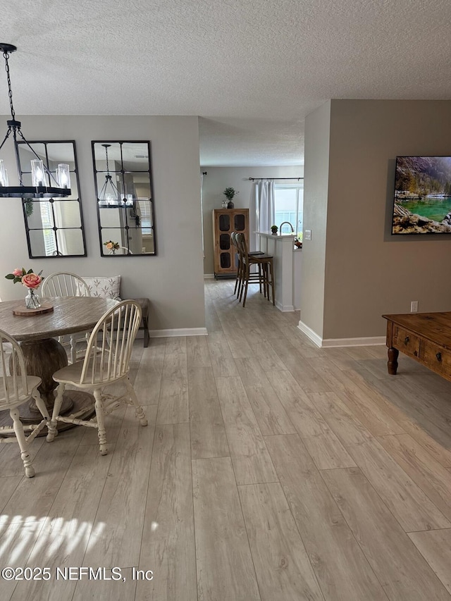 1500 Calming Water Dr Unit 5501, Fleming Island, FL 32003 - dining space featuring baseboards, a textured ceiling, light wood-style flooring, and a chandelier
