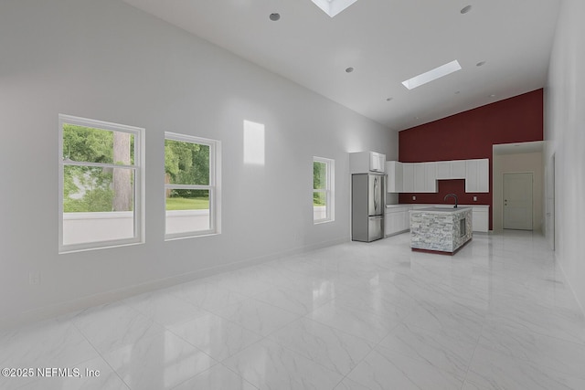 4649 Shelby Ave, Jacksonville, FL 32210 - unfurnished living room featuring high vaulted ceiling, a skylight, light marble finish floors, and healthy amount of natural light