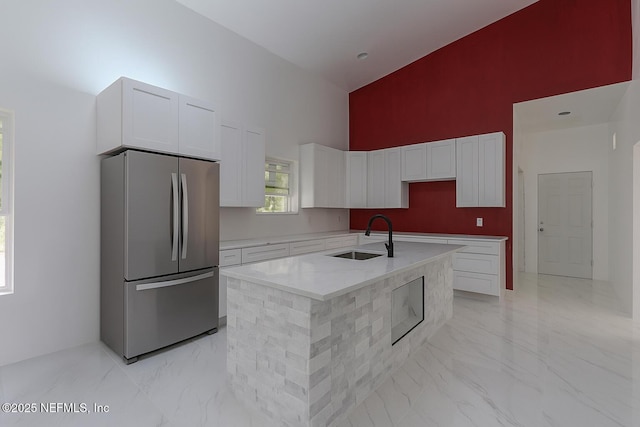 4649 Shelby Ave, Jacksonville, FL 32210 - kitchen with freestanding refrigerator, a high ceiling, white cabinetry, light marble finish flooring, and an island with sink