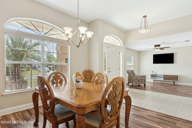 dining room featuring ceiling fan with notable chandelier, wood finished floors, and baseboards