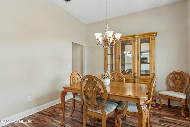dining area featuring wood finished floors, a notable chandelier, and baseboards