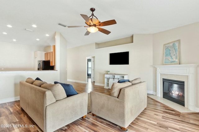 living room with recessed lighting, visible vents, a fireplace with flush hearth, and light wood-style floors
