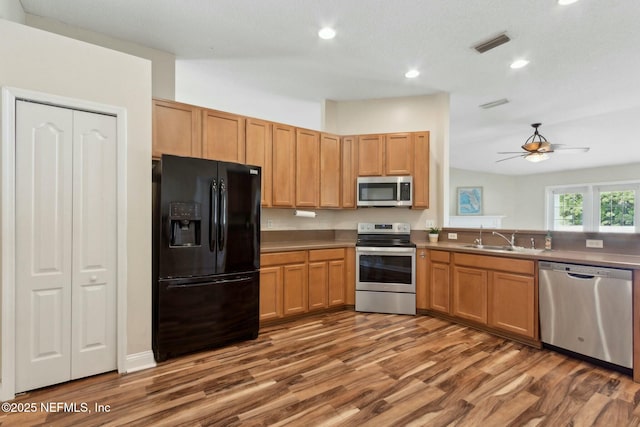kitchen with appliances with stainless steel finishes, wood finished floors, recessed lighting, and a sink