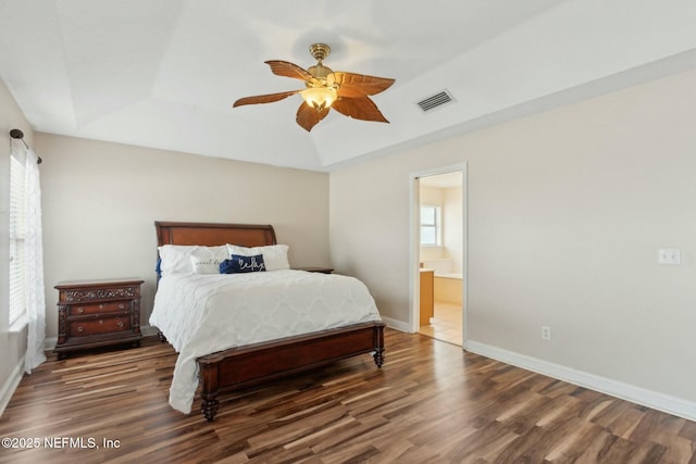 bedroom with visible vents, wood finished floors, multiple windows, and a tray ceiling