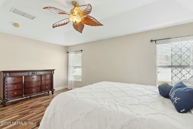 bedroom featuring a ceiling fan, visible vents, wood finished floors, and baseboards