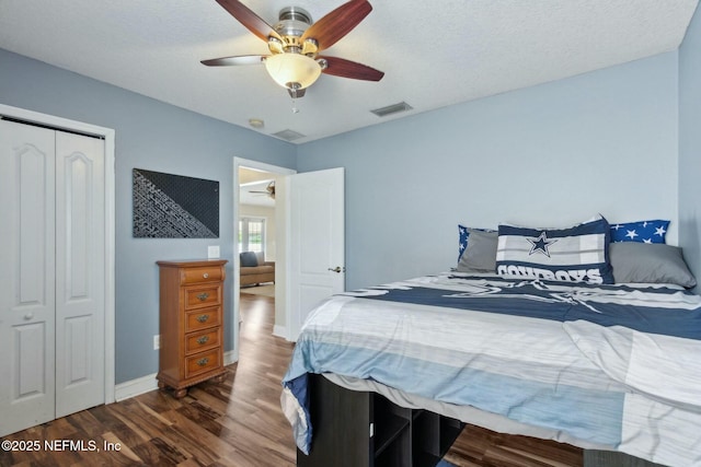 bedroom featuring dark wood-style flooring, a closet, ceiling fan, visible vents, and baseboards