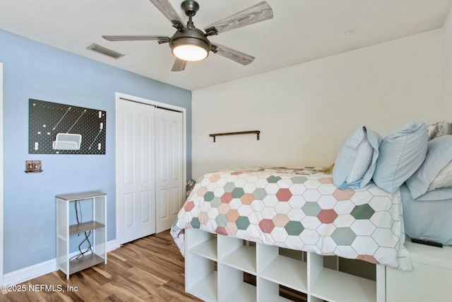 bedroom featuring wood finished floors, visible vents, ceiling fan, and a closet
