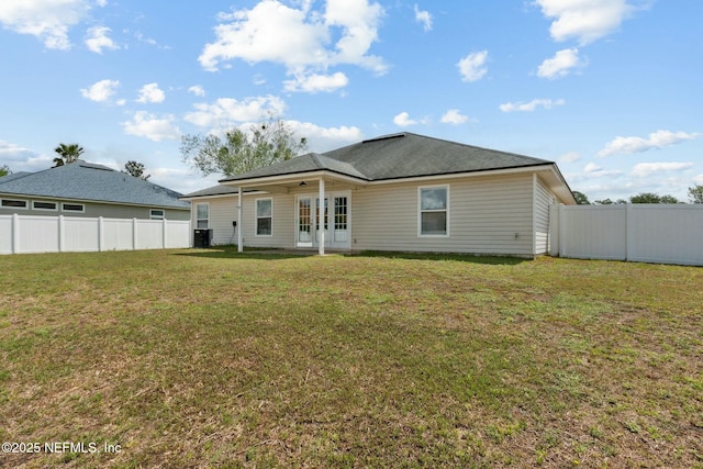 back of property with fence and a lawn