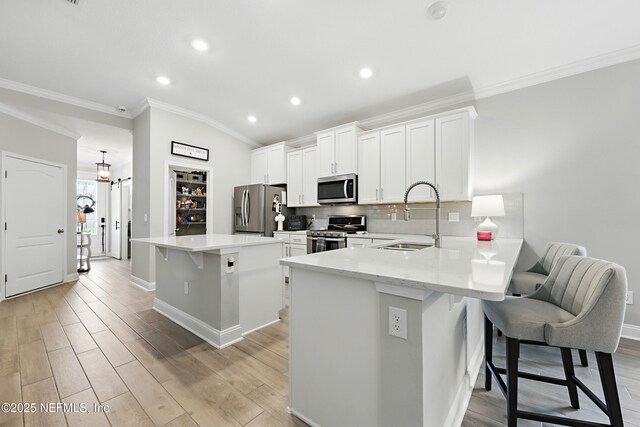 291 Greenway Ln, Saint Augustine, FL 32092 - kitchen with ornamental molding, a breakfast bar, white cabinetry, a sink, and stainless steel appliances