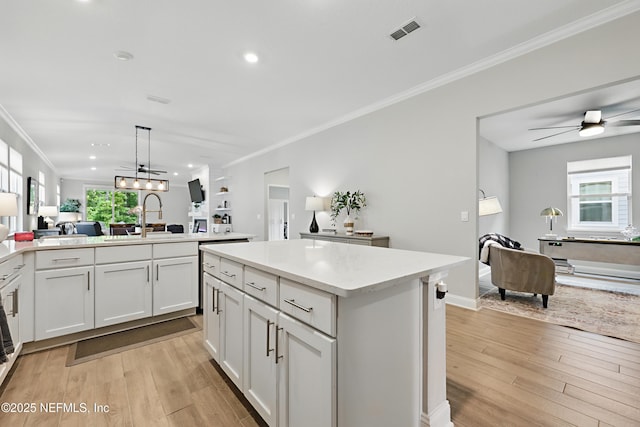 291 Greenway Ln, Saint Augustine, FL 32092 - kitchen with crown molding, open floor plan, light wood-type flooring, light countertops, and a sink