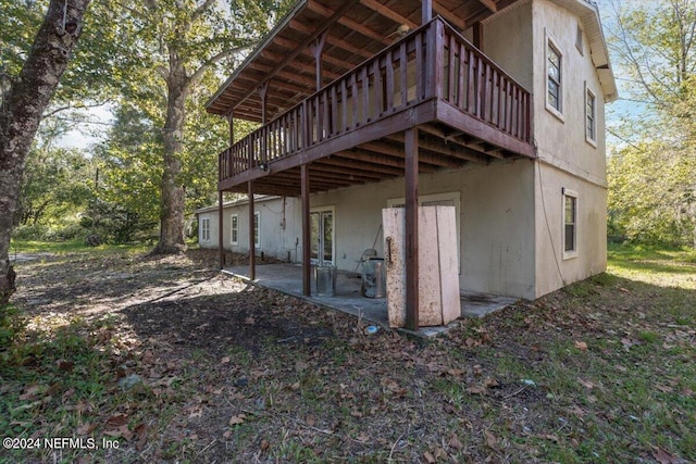 back of house featuring a wooden deck, a patio, and stucco siding
