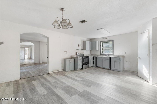 kitchen featuring arched walkways, a sink, stainless steel electric range oven, light wood-type flooring, and gray cabinetry