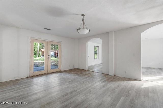 interior space featuring arched walkways, french doors, wood finished floors, and visible vents