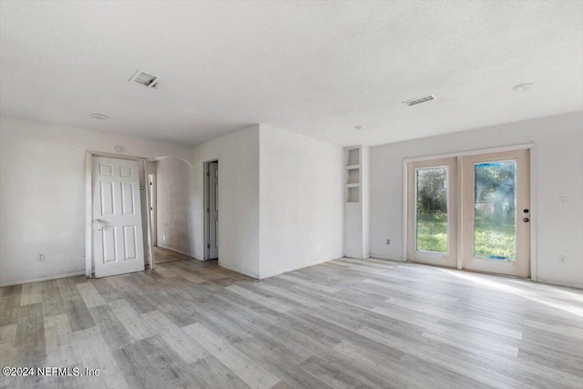 unfurnished living room featuring light wood-style flooring, visible vents, and a textured ceiling