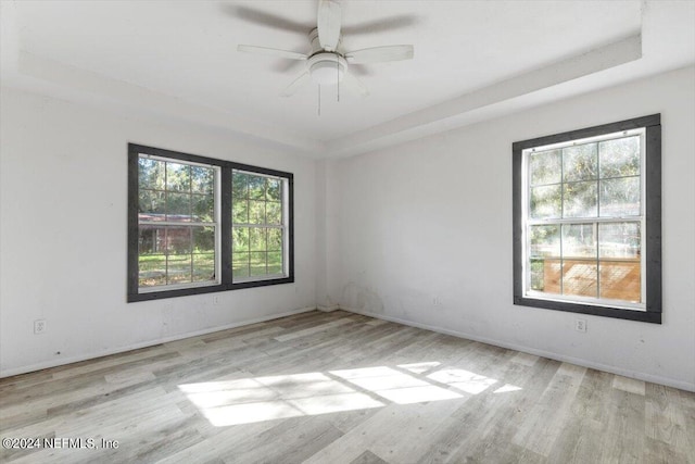 spare room featuring baseboards, wood finished floors, a raised ceiling, and ceiling fan