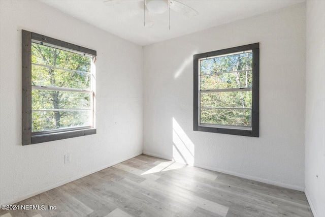 unfurnished room with wood finished floors, a textured wall, baseboards, and ceiling fan