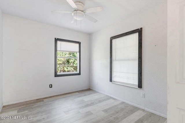 empty room with baseboards, a ceiling fan, and light wood-style flooring
