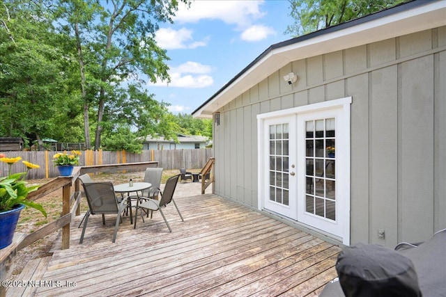 wooden deck with a fenced backyard, outdoor dining space, and french doors