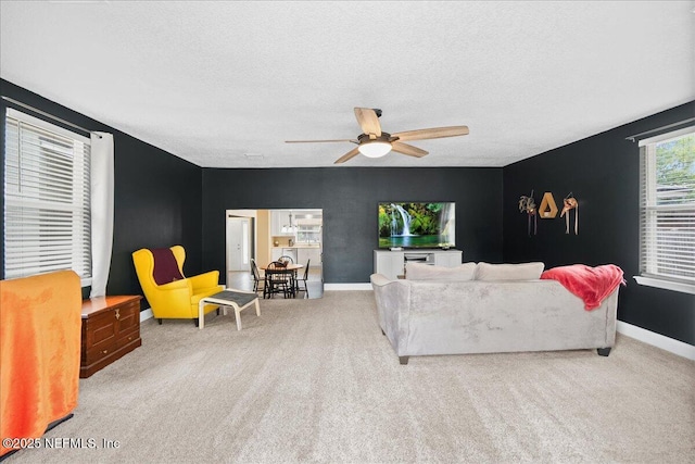 living room featuring baseboards, carpet, a ceiling fan, and a textured ceiling
