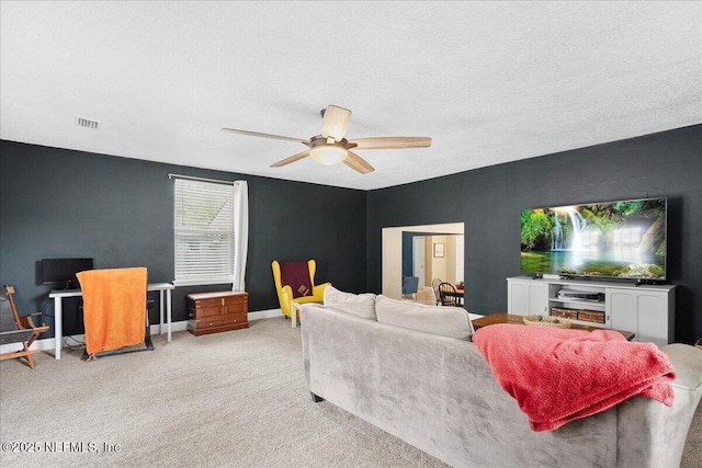 living area featuring ceiling fan, light colored carpet, a textured ceiling, baseboards, and visible vents