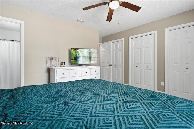 carpeted bedroom with multiple closets, a ceiling fan, a textured ceiling, and visible vents