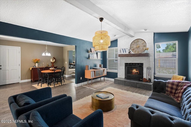 living room featuring a textured ceiling, a fireplace, wood finished floors, baseboards, and vaulted ceiling with beams