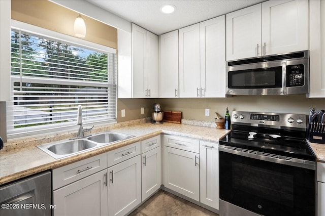 kitchen featuring light countertops, a textured ceiling, white cabinets, a sink, and stainless steel appliances