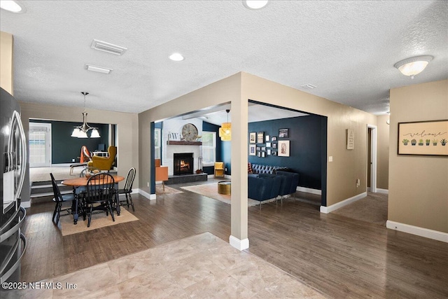 dining area featuring a fireplace, a textured ceiling, baseboards, and dark wood-type flooring