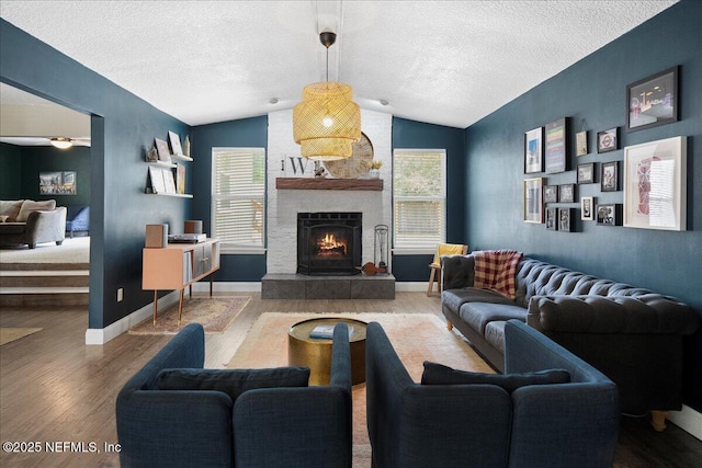 living room featuring a fireplace, vaulted ceiling, wood finished floors, and a wealth of natural light