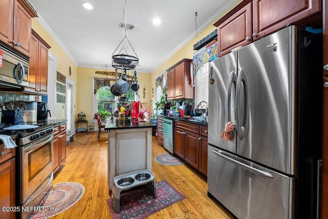 kitchen with a center island, stainless steel appliances, dark countertops, and ornamental molding
