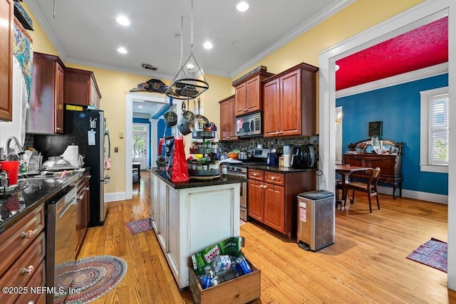 kitchen featuring tasteful backsplash, stainless steel appliances, a kitchen island, ornamental molding, and light wood-type flooring