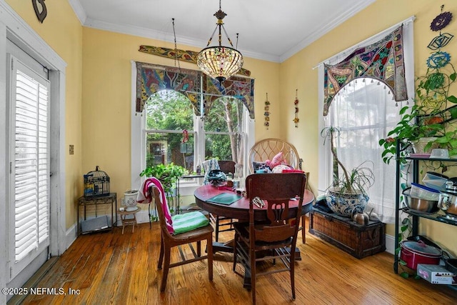 dining space with wood finished floors, ornamental molding, and baseboards