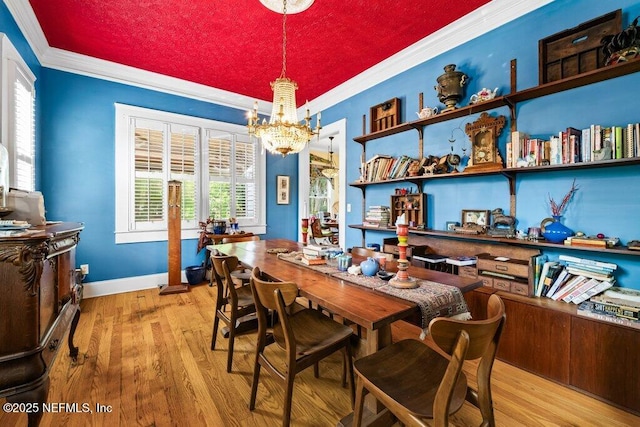 dining room with baseboards, ornamental molding, a notable chandelier, and wood finished floors